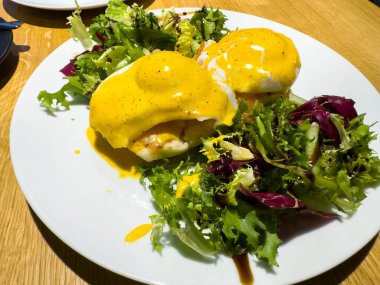 Hollandez soslu yumurta ve beyaz tabakta taze yeşil salata..