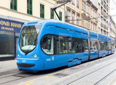 Zagreb, Hırvatistan - 14 Aralık 2025: Şehrin tarihi mimarisi, kentsel geçiş ve şehir yaşamını ön plana çıkaran mavi tramvay şehir caddesinde ilerliyor