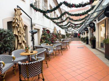 Zagreb, Hırvatistan - 14 Aralık 2025: Açık hava kafeteryasında büyüleyici bir ara sokakta festival dekorasyonları ve rahat koltuklar bulunuyor ve sıcak bir tatil atmosferi yaratılıyor