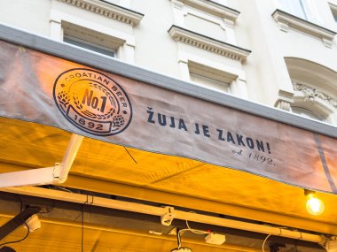 Zagreb, Hırvatistan - 14 Aralık 2025: Bar tentelerinde Zuja bira tabelası Hırvat kültürünü ön plana çıkarıyor ve müşterileri canlı bir ortamda yerel bira içmeye davet ediyor