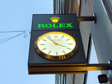 Zagreb, Hırvatistan - 14 Aralık 2025: Şatafatlı bir saat tasarımı ve tanınabilir bir taç logosu, marka prestiji ve zarafetini ön plana çıkaran alacakaranlıkta aydınlatılmış Rolex tabelası