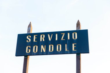 Venedik, İtalya - 19 Şubat 2025: İtalyan gondol servisi tabelaları parlak bir gökyüzüne karşı kalın harflerle yazılmış, resim ayarlarındaki seyahat ve boş zamanları simgeliyor