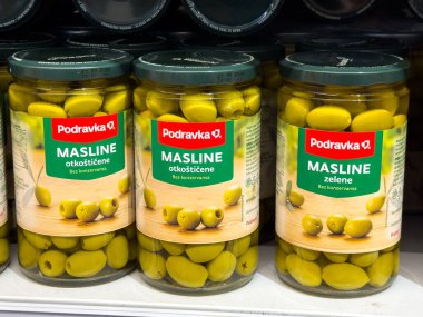 Zagreb, Hırvatistan - 17 Aralık 2025: Kavanozlardaki Podravka yeşil zeytinleri bir süpermarket rafına yerleştirilerek taze ve canlı yeşil renkleri vurgulanıyor