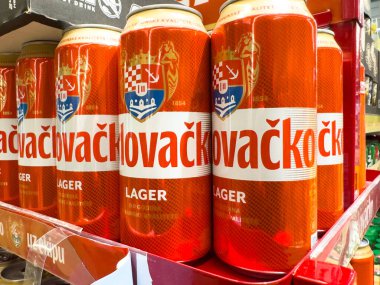 Zagreb, Hırvatistan - 17 Aralık 2025: Novacka bira kutuları bir rafa dizilerek parlak turuncu tasarım ve marka kimliğinin altı çizildi
