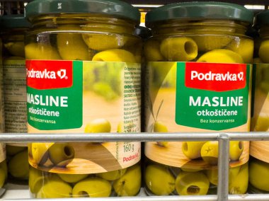 Zagreb, Hırvatistan - 17 Aralık 2025: Süpermarket raflarındaki kavanozlarda Podravka yeşil zeytinleri, taze malzemeler ve gıda aşıkları için cazip ambalajlar