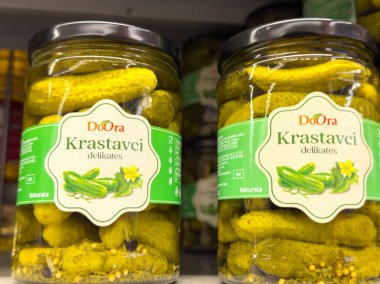 Zagreb, Hırvatistan - 17 Aralık 2025: DoOra Krastavci turşusu kavanozları tuzlu suda parlak yeşil salatalıkların yer aldığı bir rafa dizildi, taze ve cazip bir görünüm yaratıldı