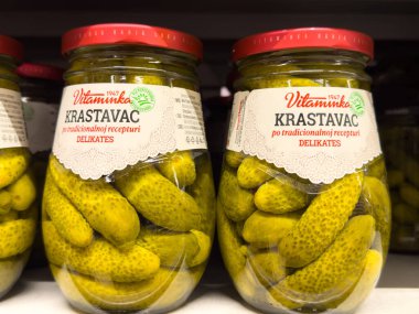 Zagreb, Hırvatistan - 17 Aralık 2025: Vitaminka Krastavac turşularının kavanozları rafta taze salatalıklar sergileyerek geleneksel tarifi ve canlı renkleri ön plana çıkarıyor