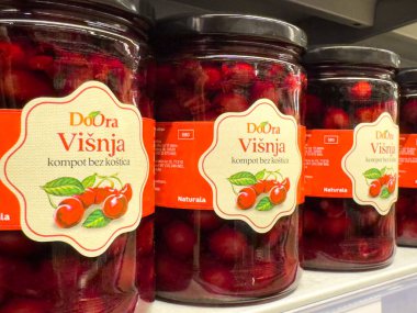 Zagreb, Hırvatistan - 17 Aralık 2025: DoOra Visnja kiraz ezmesi kavanozları bir rafta sergilenerek, kirazların zengin rengini ve çekici etiketleri ön plana çıkarıyor