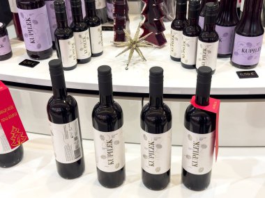 Zagreb, Hırvatistan - 17 Aralık 2025: Kupilek şarap şişeleri şık etiketler ve şenlikli dekorlarla bir masaya dizilerek sıcak bir tatil ortamı yaratıldı