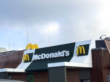 Bled, Slovenya - 17 Aralık 2025: McDonald 's servis levhası bulutlu bir gökyüzünün altındaki çağdaş bir binada açıkça görülüyor, markanın ikonik varlığını vurguluyor