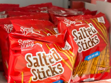 Bled, Slovenya - 17 Aralık 2025: Atıştırmalık Günü Tuzlu Çubuklar, parlak kırmızı paketleme ve cazip atıştırmalık cazibesinin yer aldığı bir market rafına güzelce yerleştirildi