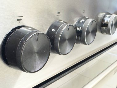 Zagreb, Hırvatistan - 17 Aralık 2025: Siyah kadranlı paslanmaz çelik fırın düğmelerinin yakın plan resmi, sıcaklık ayarları ve modern mutfak estetiği