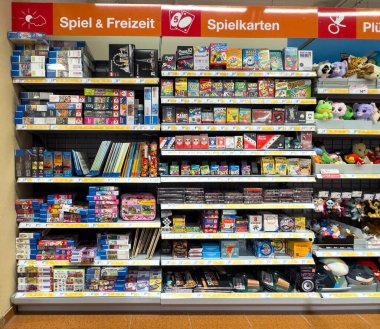 Villach, Avusturya - 13 Aralık 2025: Bir perakende mağazasında oyun, kart oyunları ve oyuncaklarla dolu canlı raflar, aile eğlencesi ve eğlence için mükemmel