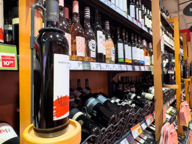 Villach, Avusturya - 13 Aralık 2025: Bir perakende mağazasında raflara dizilmiş şarap şişeleri, çeşitli etiketler ve renkler, alışveriş deneyimini artıran