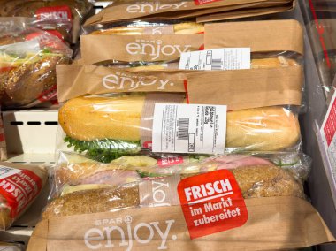 Villach, Avusturya - 13 Aralık 2025: SPAR 'dan paketli sandviçler, bir market ortamında taze malzemeler ve canlı renkler sergiliyor.