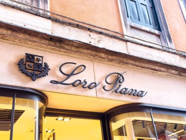 Venedik, İtalya - 05 Aralık 2025: Loro Piana mağaza vitrininde lüks moda ve tekstil keşfi için müşterileri davet eden şık tabelalar ve karmaşık mimari yer alıyor