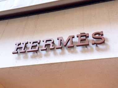 Venedik, İtalya - 05 Aralık 2025: Hermes logosu, lüks markalaşma ve sofistike perakende atmosferi ön plana çıkaran bej renkli düz bir duvarda sergilenmektedir.