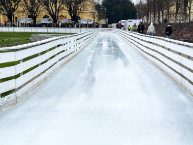 Zagreb, Hırvatistan - 14 Aralık 2025: Buz pateni sahasında beyaz çitler ve kış etkinliklerinin keyfini çıkaran insanlar canlı bir kış manzarası yaratıyor