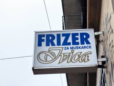 Zagreb, Hırvatistan - 14 Aralık 2025: İvica adlı erkekler için berber dükkânı tabelası, mavi ve altın renkler sergileniyor, yerel işletme ve toplumsal bağlantıyı vurguluyor