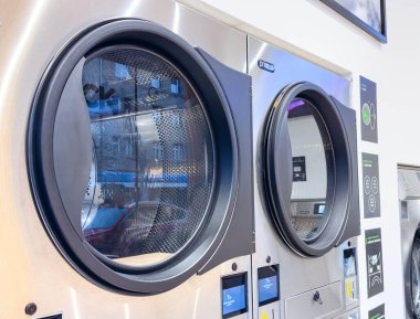 Zagreb, Hırvatistan - 14 Aralık 2025: Çağdaş çamaşır makineleri şeffaf kapılar içererek, fotokopi alanına sahip parlak, organize bir çamaşırhanede çamaşır sürecini ortaya çıkardı