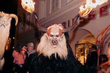Sankt Veit A D Glan, Avusturya - 4 Ocak 2025: Krampuslauf etkinliği, Krampus 'un ateşli meşaleleriyle etrafı şenlikli kış şenlikleriyle çevrili tehditkar bir figürünü sergiliyor
