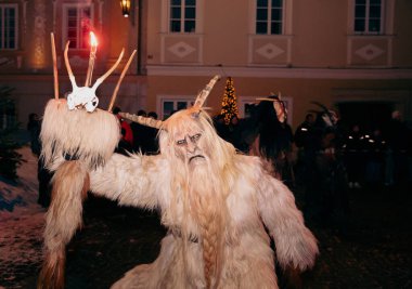 Sankt Veit A D Glan, Avusturya - 4 Ocak 2025: Krampuslauf etkinliği, canlı bir bayram kutlamasının ortasında el feneri tutan Krampus karakterini sergiliyor
