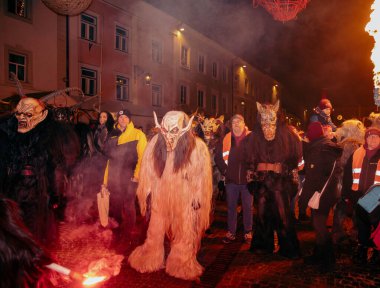 Sankt Veit A D Glan, Avusturya - 4 Ocak 2025: Krampuslauf etkinliği, kalabalık ve ışıldayan meşalelerle çevrili, karmaşık kostüm ve maskeli kişileri sergiliyor