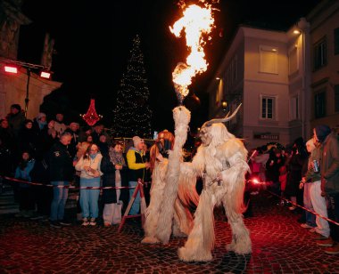 Sankt Veit A D Glan, Avusturya - 4 Ocak 2025: Krampuslauf festivalinde alevler içinde kürklü kostümler içindeki göstericiler, tezahürat yapan kalabalığın arasında canlı bir atmosfer yarattı