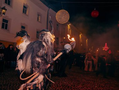 Sankt Veit A D Glan, Avusturya - 4 Ocak 2025: Krampuslauf kutlamaları, büyüleyici bir caddede boynuzlu bir şahıs, canlı ışıklar ve hareketli bir kalabalık sergiliyor.