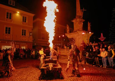 Sankt Veit A D Glan, Avusturya - 4 Ocak 2025: Krampuslauf kutlama gösterileri, coşkulu bir kasaba ortamında kalabalık tarafından çevrelenmiş, alevli kostümler içinde gösteriler düzenliyor.