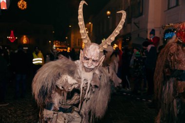 Sankt Veit A D Glan, Avusturya - 4 Ocak 2025: Krampuslauf canlı bir sokakta boynuzlu bir figürle kutlama, şenlikli süslemeler ve izleyicilerle çevrili