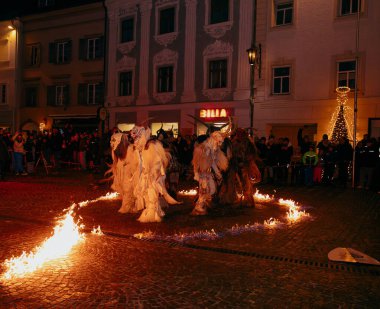 Sankt Veit A D Glan, Avusturya - 4 Ocak 2025: Krampuslauf etkinliği, ateşin etrafında dans eden, şenlik ruhu ve kültürel mirası somutlaştıran karmaşık kostümler içindeki sanatçıları sergiliyor