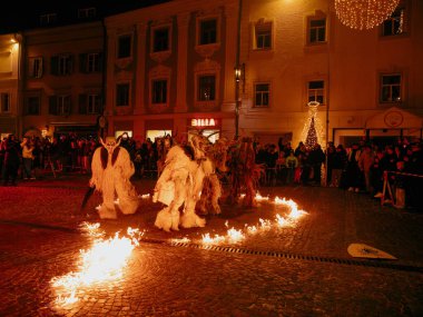 Sankt Veit A D Glan, Avusturya - 4 Ocak 2025: Krampuslauf etkinliği, canlı bir kasaba meydanında alevler içinde dans eden süslü kostümlü sanatçılarla