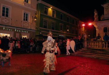 Sankt Veit A D Glan, Avusturya - 4 Ocak 2025: Krampuslauf Festivali, seyircilerle dolu canlı bir caddede yürüyen geleneksel kıyafetli bir kişiye yer veriyor.