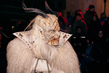 Sankt Veit A D Glan, Avusturya - 4 Ocak 2025: Krampuslauf etkinliği, arka planda şenlik kalabalığı ile ayrıntılı kostüm giymiş korkutucu Krampus figürünü sergiliyor