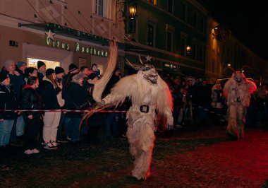 Sankt Veit A D Glan, Avusturya - 4 Ocak 2025: Krampuslauf etkinliği, büyüleyici bir izleyici kitlesi tarafından çevrelenmiş, sokaklarda yürüyen ayrıntılı kostümlü sanatçılar