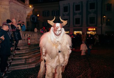 Sankt Veit A D Glan, Avusturya - 4 Ocak 2025: Krampuslauf kutlamaları, özenle hazırlanmış kostümlü boynuzlu bir figürü, gece hareketli kalabalıklarla meşgul ediyor.