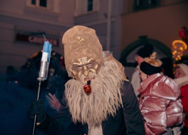 Sankt Veit A D Glan, Avusturya - 4 Ocak 2025: Krampuslauf kutlamalarında kürk maskeli ve kadrolu kostümlü bir şahıs coşkulu bir kalabalığın ortasında sergileniyor
