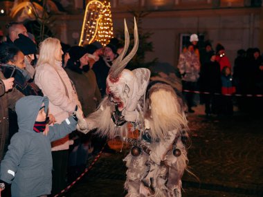 Sankt Veit A D Glan, Avusturya - 4 Ocak 2025: Krampuslauf etkinliği, bir Krampus karakterine uzanan bir çocuk içermektedir.
