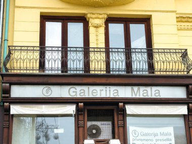 Zagreb, Hırvatistan - 16 Aralık 2025: Galerija Mala 'nın demirden balkon ve sarı cepheli mağazası davetkar bir kentsel atmosfer yarattı