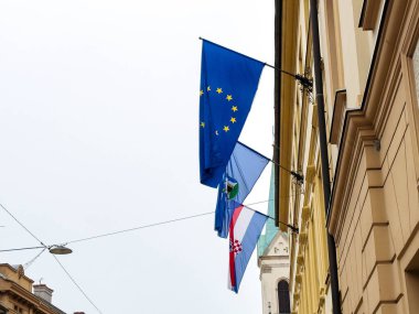 Zagreb, Hırvatistan - 16 Aralık 2025: Avrupa Birliği ve Hırvatistan 'ın bayrakları, kentsel çevrede birlik ve kültürel önemi temsil ederek inşaattan sarkıyor