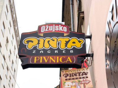 Zagreb, Hırvatistan - 16 Aralık 2025: Özujsko Pinta tabelasında parlak renkler ve kalın harfler yer alıyor, müşterileri yerel bar atmosferi ve lezzetli mutfağın tadını çıkarmaya davet ediyor