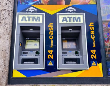 Zagreb, Hırvatistan - 16 Aralık 2025: Açık 'ATM' işareti ve renkli bir duvara yerleştirilmiş '24 saat nakit' etiketli iki ATM, kentsel kolaylığı vurguluyor