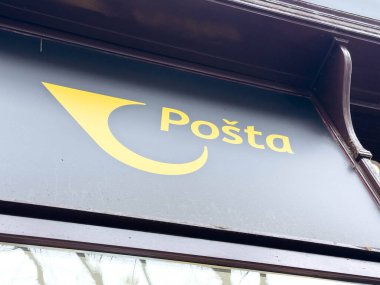 Zagreb, Hırvatistan - 16 Aralık 2025: Posta tabelasında, canlı kentsel bir ortamda fotokopi alanı ile birlikte posta hizmetlerini temsil eden koyu arkaplan üzerinde sarı bir logo görülüyor