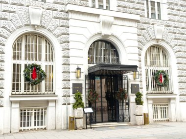 Zagreb, Hırvatistan - 16 Aralık 2025: Bina girişinde tatil çelenkleri ve kırmızı kurdeleler yer alıyor, fotokopi alanına sahip kentsel bir ortamda şenlikli bir atmosfer yaratılıyor