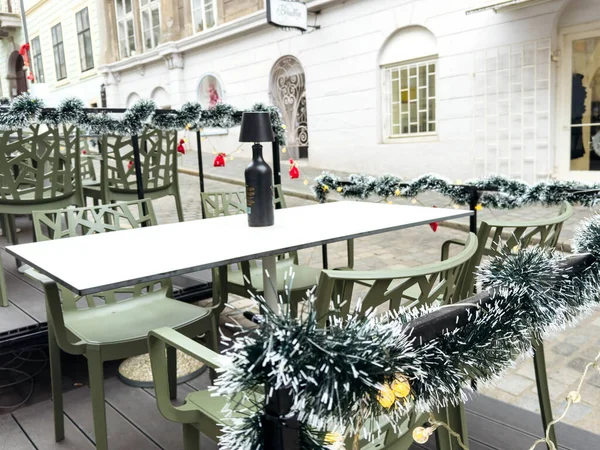 Zagreb, Hırvatistan - 16 Aralık 2025: Açık hava yemek düzeninde, bayram toplantıları için mükemmel olan yeşil sandalyeler ve beyaz masa süsleri yer alıyor