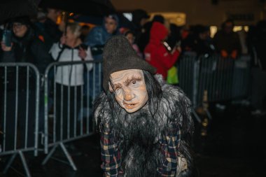 Villach, Avusturya - 01 Aralık 2023: Krampuslauf etkinliğinde maskeli ve kürklü kostümlü bir karakter festival ortamında neşeli bir kalabalığa takılıyor