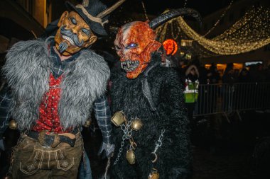 Villach, Avusturya - 01 Aralık 2023: Krampus gibi giyinmiş iki kişi, Krampuslauf 'taki canlı festival sırasında karmaşık maske ve kürk kostümleri sergiliyorlar.