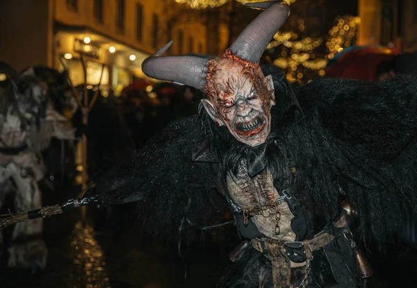Villach, Avusturya - 01 Aralık 2023: Krampuslauf etkinliği, tatil sezonunun neşeli ama ürkünç ruhunu somutlaştıran koyu renk kostümlü boynuzlu bir şahsiyeti sergiliyor