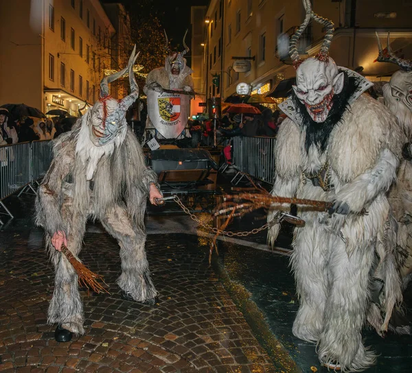 Villach, Avusturya - 01 Aralık 2023: Krampuslauf etkinliğinde boynuzlu kostümlü erkekler, kışın gelenekleri canlı bir sokak sahnesinde fotokopi uzayıyla kutlanıyor
